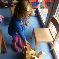 Ein Mädchen baut mit Holzbausteinen