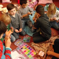 Eine Gruppe von Mädchen und Jungen knien auf dem Teppich und spielen mit Perlen