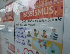 Bunte Plakate gegen Rassismus hinter einer Scheibe