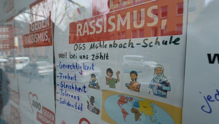 Bunte Plakate gegen Rassismus hinter einer Scheibe