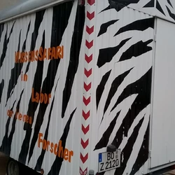 Ein schwarz-weiß angestrichener Bauwagen mit der Aufschrift Wissenssafari im Labor der kleinen Forscher