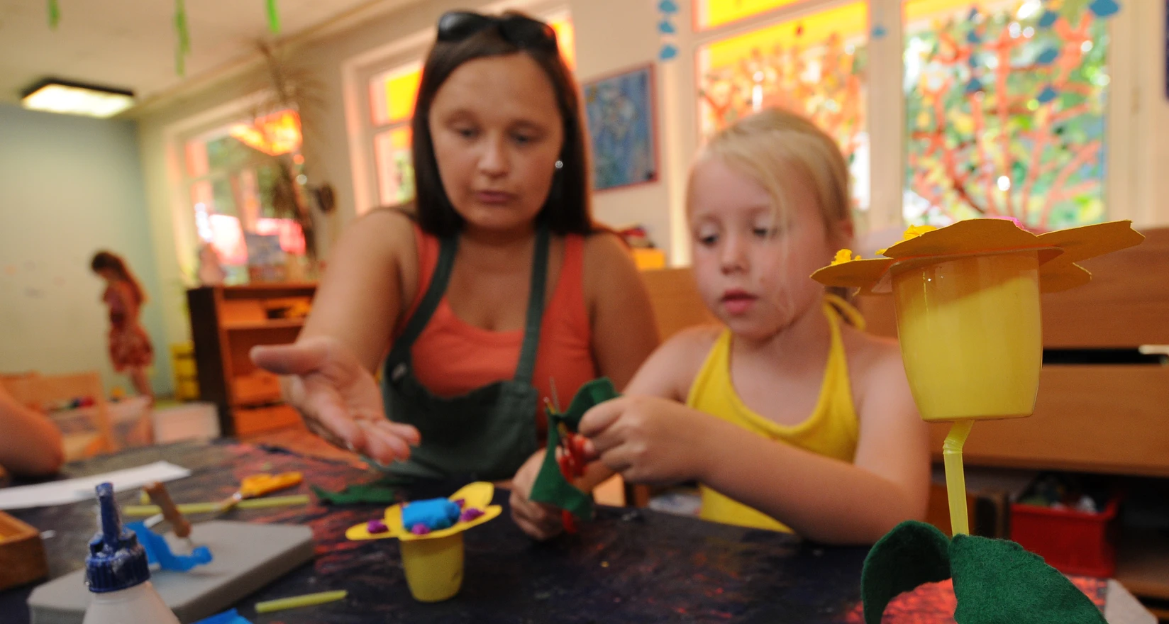 Erzieherin und Kind basteln