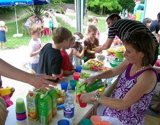 Kinder bedienen sich an einem Stand mit Obst und Getränken
