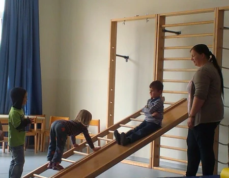 Drei Kinder mit ihrer Erzieherin turnen
