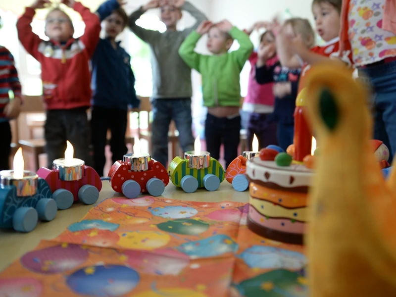 Kindergruppe feiert Geburtstag - Stuhlkreis im Hintergrund, mittig ein Geburtstagszug,  vorne eine Ente