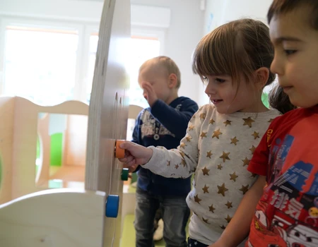 Drei Kinder spielen mit einem beweglichen Holzspielzeug