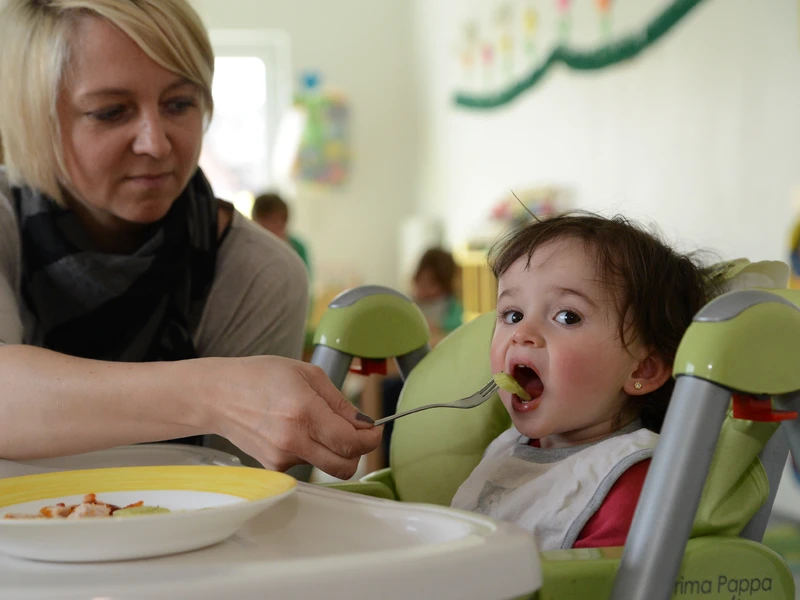 Erzieherin füttert ein U3-Kind