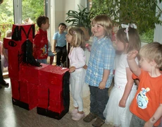 Kinder mit einem roten Pferd aus Pappe