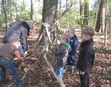 Kinder bauen im wald ein Tipi aus Ästen
