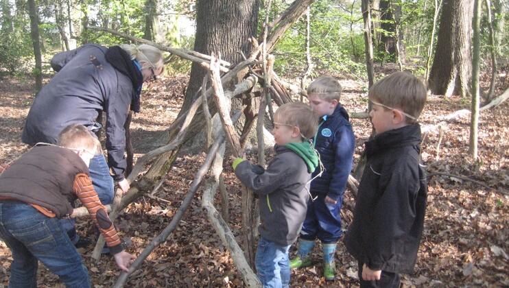 Kinder bauen im wald ein Tipi aus Ästen