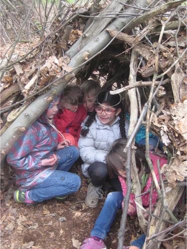 Kinder spielen im Wald unter geschichteten Ästen
