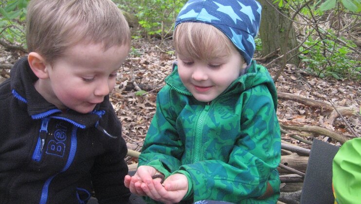 Zwei Kinder im Wald betrachten ein Fundstück