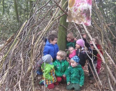Kinder im wald unter aufgeschichteten Ästen mit einer selbst bemalten Fahne