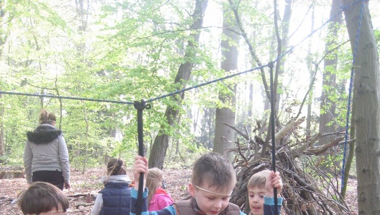 Jungen spielen im Wald an einer selbst gebauten Schaukel