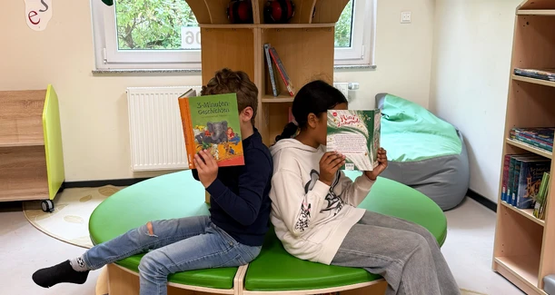 Zwei Kinder sitzen in der LeseOase und lesen ein Buch.