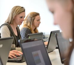 Schülerinnen arbeiten an ihren Laptops