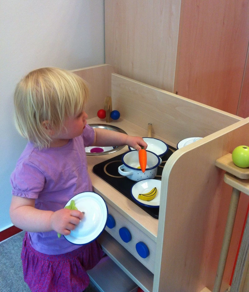 Ein Mädchen spielt in der hölzernen Kinderküche