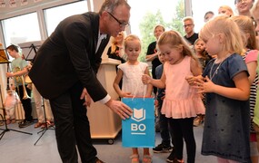 Ein Vertreter der Stadt Bochum überreicht drei kleinen Mädchen eine Tüte mit dem Logo der Stadt