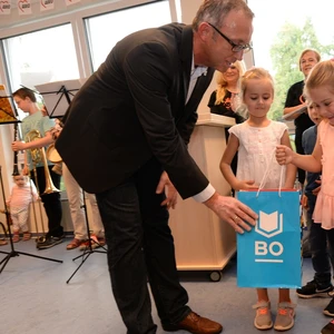 Ein Vertreter der Stadt Bochum überreicht drei kleinen Mädchen eine Tüte mit dem Logo der Stadt