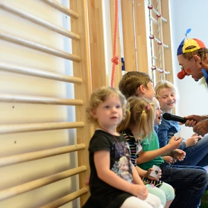 Ein Clown reicht den Kindern ein Mikrofon