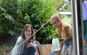 Lachende Frau und Mädchen mit Wasserspritzflasche