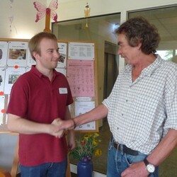 Der FSKLer Danile und der Leiter des Seniorenzentrums vor einer Infotafel, sie schütteln sich die Hand