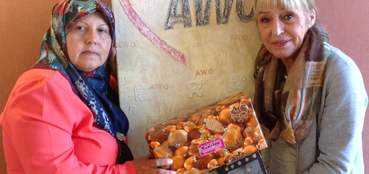 Zwei frauen präsentieren Weihnachtspäckchen vor einem Bild mit dem AWO-Logo